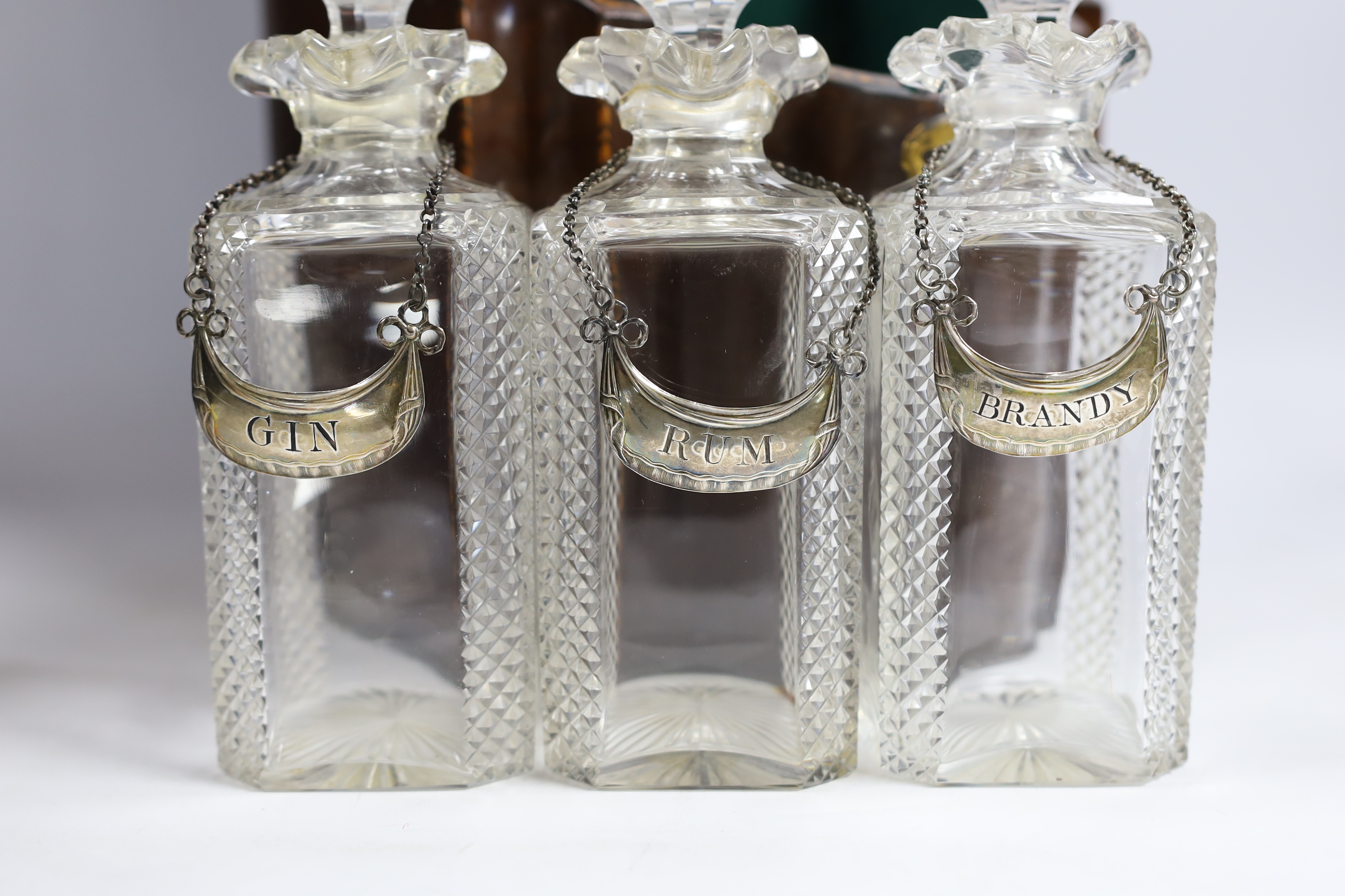 A tantalus with three decanters and three George III silver crescent shaped wine labels, Nathaniel Smith & Co, Sheffield, circa 1790.